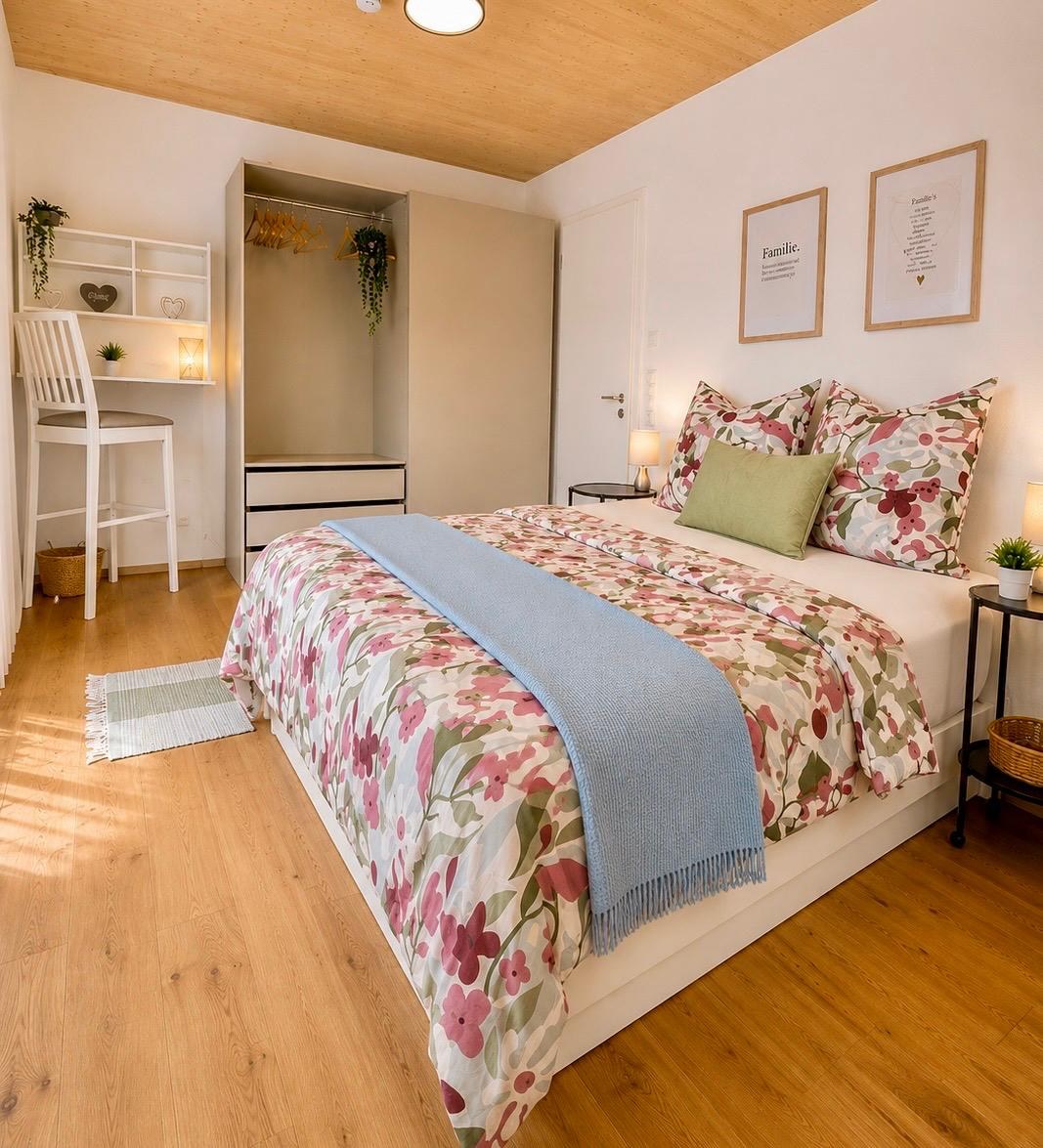 Schlafzimmer mit Doppelbett, floraler Bettwäsche und kleinem Schreibtisch